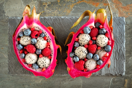Colorful dragon fruit salads with raspberries and blueberries over a slate backgroundの写真素材