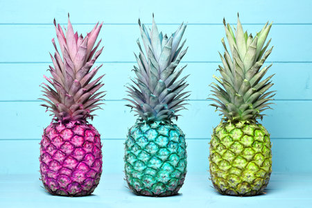 Pineapples of different color hues on a pastel blue wooden backgroundの写真素材