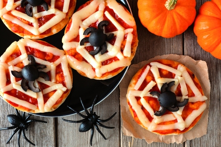 Halloween spider web mini pizzas overhead scene on a rustic wooden backgroundの写真素材