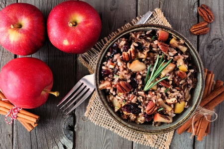 Autumn rice pilaf with apples, nuts and cranberries, overhead scene against a rustic wood backgroundの写真素材