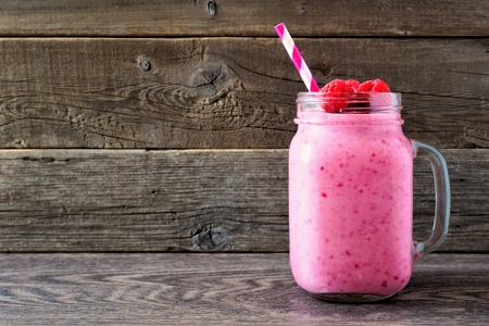 Raspberry smoothie in a mason jar mug over a rustic wood backgroundの写真素材