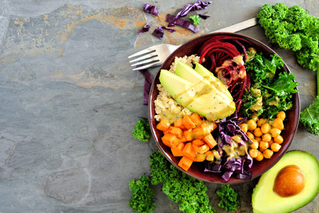 Buddha bowl with quinoa, avocado, chickpeas, vegetables on a dark background. Healthy food concept....