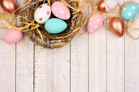 Springtime nest with pink, rose gold and turquoise painted Easter Eggs. Top border against a rustic...