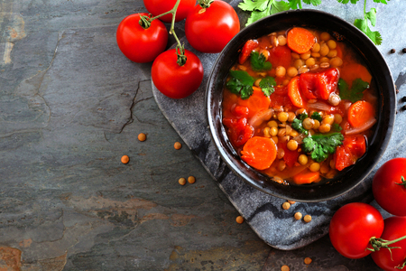 Homemade tomato, lentil soup, above view corner border with copy space on a dark slate backgroundの写真素材