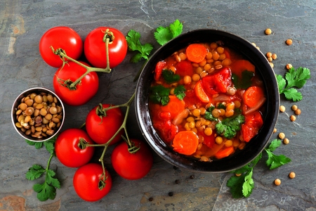 Homemade tomato, lentil soup, overhead scene, flat lay on a dark slate backgroundの写真素材