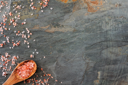 Side border of pink Himalayan salt with spoon. Top view on a dark stone background.の写真素材