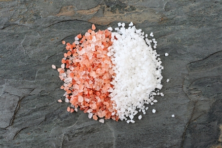Pile of half pink Himalayan and half sea salt. Top view on a dark background. Comparison concept.の写真素材