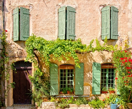 Rustic house front with green wooden shuttered windows and leafy facade, Provence, Franceの写真素材