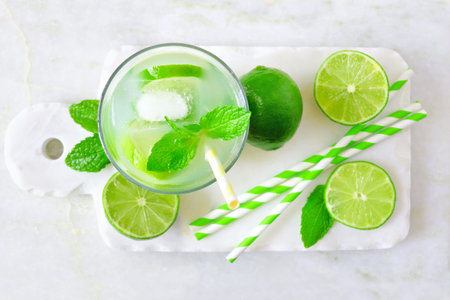 Summer limeade in a glass. Top view on a marble server against a bright background.