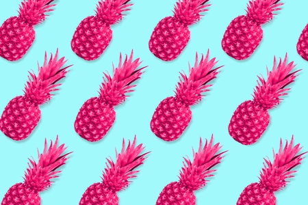Colorful fruit pattern. Neon pink pineapples on a pastel blue background. Top view.の写真素材