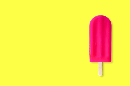 Single pink ice cream pop against a bright yellow background with copy space. Minimal summer concept.の写真素材