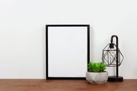 Mock up black frame, succulent plant and industrial style lamp on a shelf or desk. Wood shelf and...