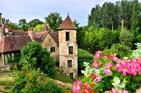Old medieval house and tower with flowers in the quaint village of Carennac, Franceのeditorial素材