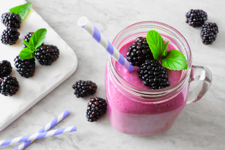 Healthy blackberry smoothie in a mason jar glass. Close up, downward view table scene against a white marbleの写真素材