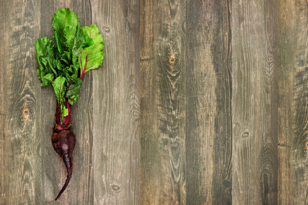 Single fresh beetroot with leaves, side orientation on a rustic wood background with copy spaceの写真素材