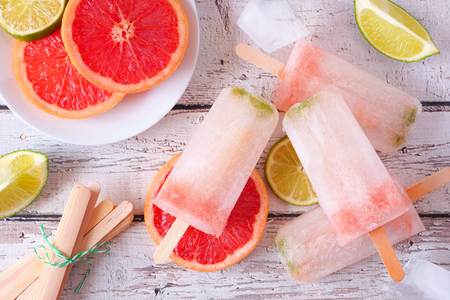 Sparkling lime and grapefruit ice lolly, top view table scene against a white wood backgroundの写真素材