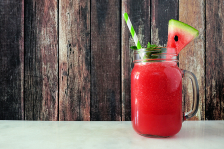 Watermelon juice in a mason jar, side view against dark woodの写真素材