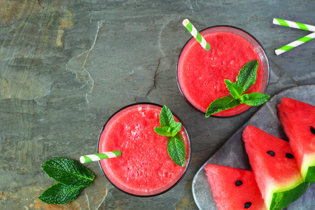 Watermelon juice in two glasses, top view over a dark stone background with copy spaceの写真素材