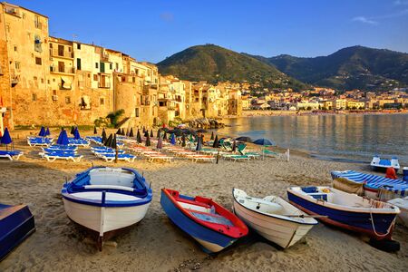 Beach and picturesque old harbor at sunset with wooden fishing boats, Cefalu, Sicily, Italyの写真素材