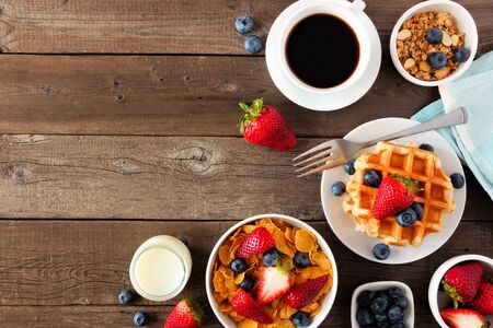 Breakfast food corner border of fruits, cereal, waffles, milk and coffee, top view over a dark wood background with copy spaceの写真素材