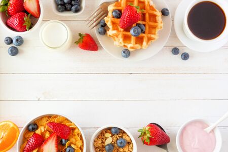 Breakfast food double border of fruits, cereal, waffles, yogurt, milk and coffee, top view over a white wood background with copy spaceの写真素材