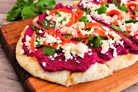 Beet hummus flat bread with feta cheese close up on a wood backgroundの写真素材