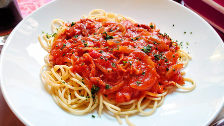 Fresh Italian spaghetti with a pepper and tomato sauce, close up on a white plateの写真素材