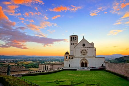 Basilica of San Francis of Assisi at sunset under beautiful glowing orange and blue skies, Italyの写真素材