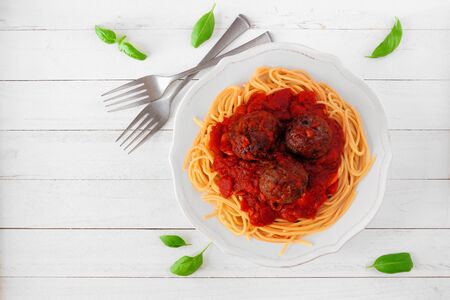 Spaghetti and meatballs with tomato sauce, above view on white woodの写真素材