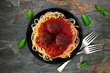 Spaghetti and meatballs with tomato sauce, top view on a dark stone backgroundの写真素材