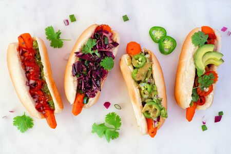 Carrot hot dogs with assorted toppings, top view on a white marble backgroundの写真素材