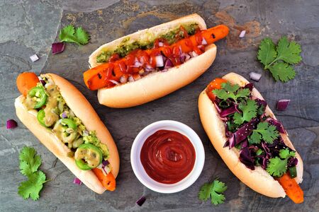 Carrot vegan hot dogs with assorted toppings, top view on a slate backgroundの写真素材