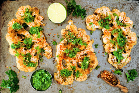 Cauliflower steaks top view on a rustic baking tray, healthy plant based meat substitute conceptの写真素材
