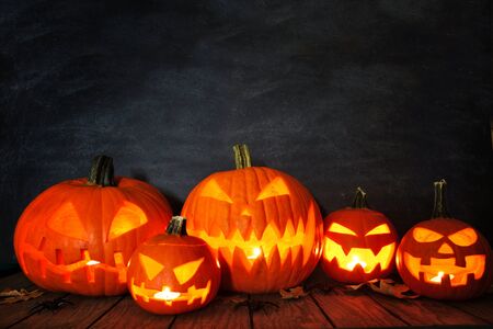 Group of illuminated Halloween Jack o Lanterns at night with a dark backgroundの写真素材
