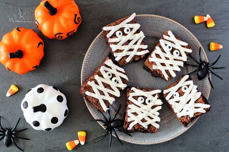 Halloween mummy brownies, top view with decor on a dark stone backgroundの写真素材