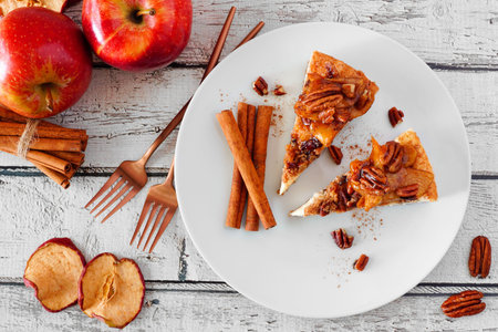 Two slices of autumn caramel apple pecan cheesecake, top view table scene over white woodの写真素材