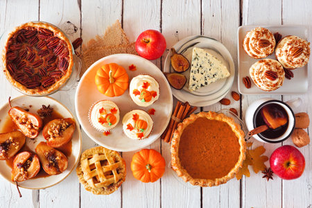Autumn food table scene with pies, appetizers and desserts, top view over a white wood background