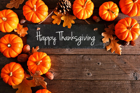 Happy Thanksgiving chalkboard sign with corner border of pumpkins and leaves over a rustic wood...
