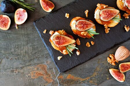 Crostini appetizers with figs, brie cheese and walnuts, top view on a slate serving boardの写真素材