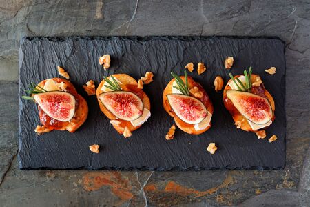 Appetizers with figs, brie cheese and walnuts, above view on a slate platterの写真素材