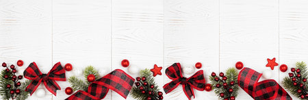 Christmas border banner of ornaments, branches and red and black checked buffalo plaid ribbon, top...