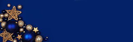 Christmas corner border banner of dark blue and gold ornaments, overhead on a midnight blue backgroundの写真素材