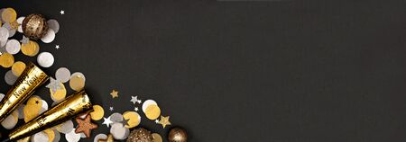 New Years Eve corner border banner of confetti, decorations and noisemakers, overhead view on a black backgroundの写真素材