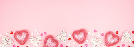Valentines Day banner with long border of pink and white heart decorations against a pink