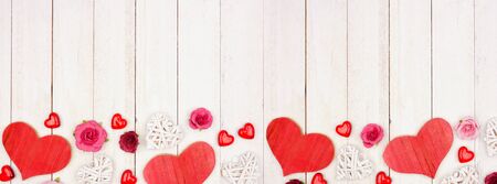 Valentines Day banner with border of hearts, flowers and decor against a white woodの写真素材
