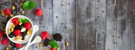 Healthy yogurt with fresh berries and granola, banner with corner border against a rustic wood...