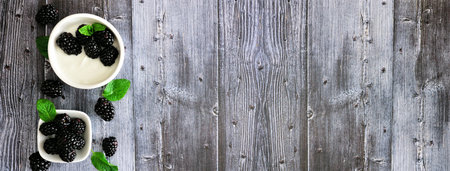 Healthy yogurt with fresh blackberries banner with side border against a rustic wood background with...