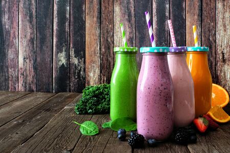 Various healthy smoothies in bottles with ingredients, side view against a wood backgroundの写真素材