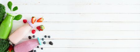 Banner with corner border of assorted healthy smoothies in bottles against a white wood background with copy spaceの写真素材