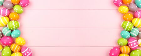 Colorful Easter banner with a double sided border of Easter Eggs over a pink wood background with copy spaceの写真素材